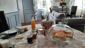 A dining table set with various food items, including bread, jams, and a bottle of orange juice.