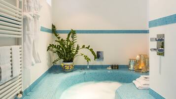 Bathroom features a large bathtub, blue-tiled walls and floor, and a potted plant.