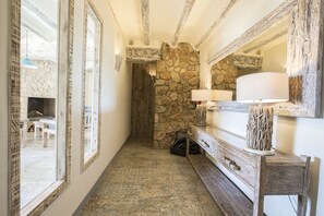 A narrow hallway with stone walls, a wooden bench, and a mirror. - Mas del Sord 1335 (L'Albiol)
