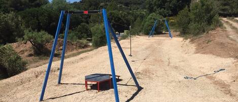 A playground with swings and a trampoline in a natural setting.