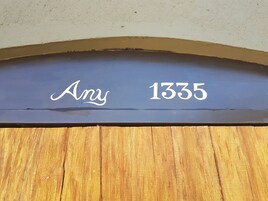 Una puerta de madera con un letrero azul oscuro encima que muestra el nombre 