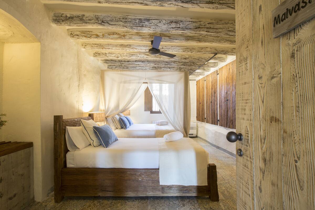 A bedroom with a wooden bed, a ceiling fan, and a wooden door.
