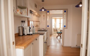 Une cuisine avec un plan de travail en bois, une bouilloire, une machine à café et une bouteille d’eau.