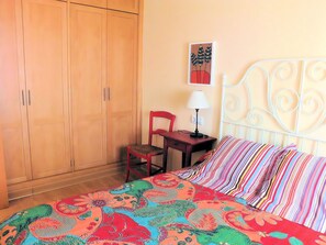 Une chambre à coucher avec un lit, une chaise, un bureau et une armoire.