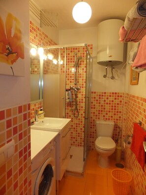 Une petite salle de bain comprenant une douche, des toilettes et un lavabo.