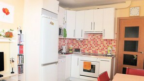 A compact kitchen with white cabinets, a microwave, a stove, and a red and white tiled backsplash. - Cute and quiet, in the city center, paid parking (Sevilla)