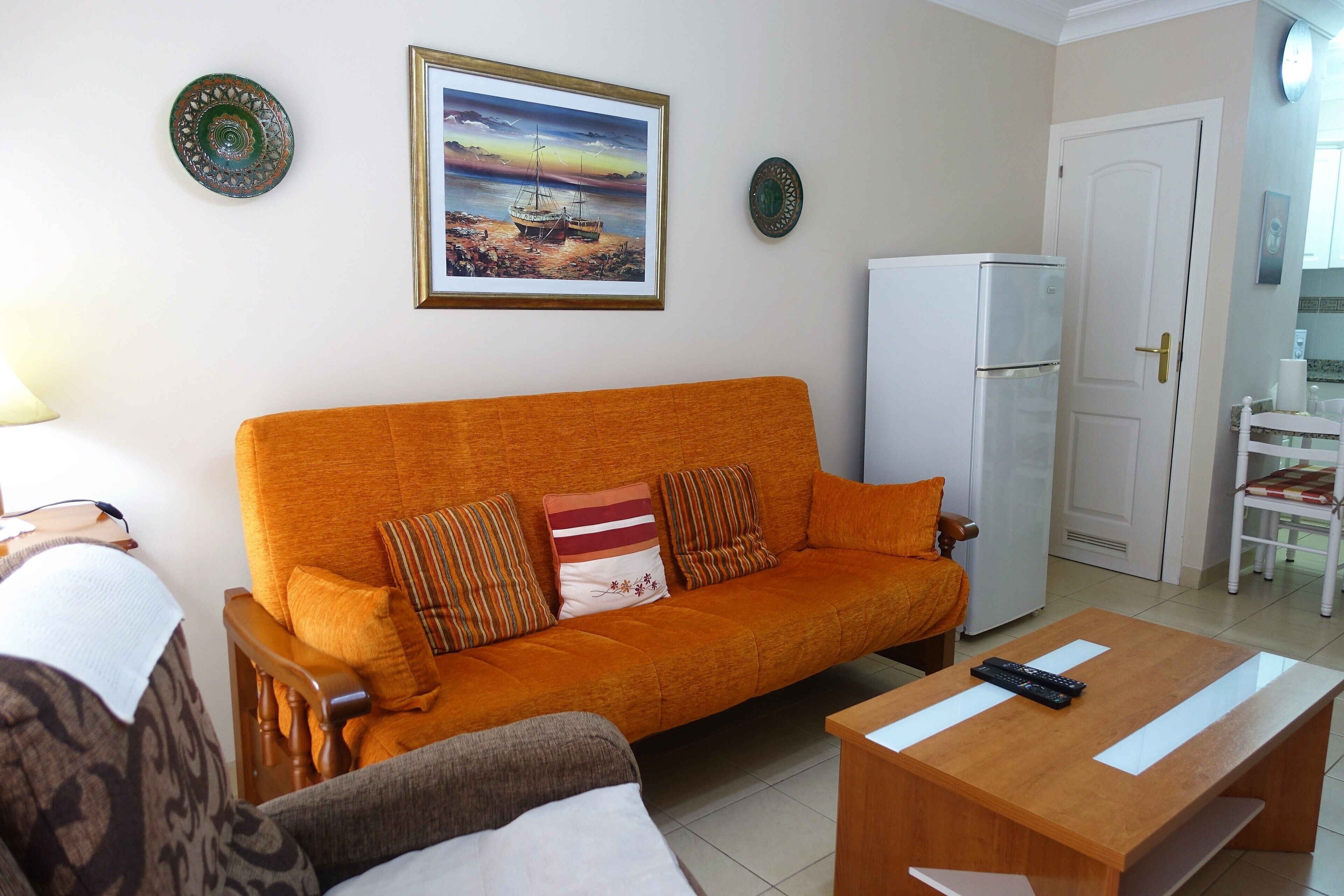 A living room with a sofa, a coffee table, and a refrigerator.