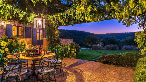 An outdoor patio with a round table and chairs, a lantern, and a view of a hillside. - Muffato 6, Emma Villas (Sarteano)