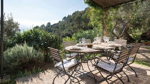 Un área de comedor al aire libre con una mesa redonda, bancos y una pérgola.