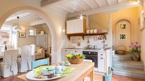 Una cocina acogedora con armarios blancos, encimera de madera y una lámpara colgante.