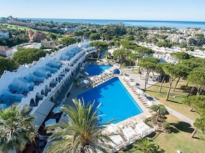 Ein Resort mit einem großen Pool, einer überdachten Lounge-Bereich und Blick auf das Meer.