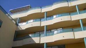 A multi-story building with balconies, a flat roof, and a clear sky.