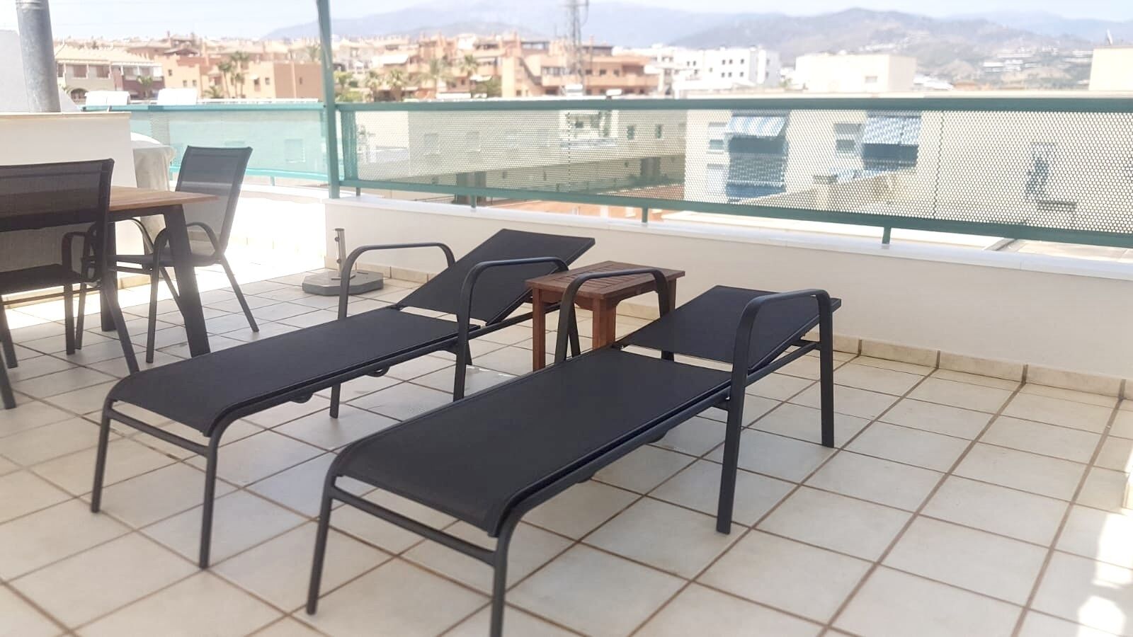 Een balkon met betegelde vloer, een tafel en vier comfortabele stoelen.