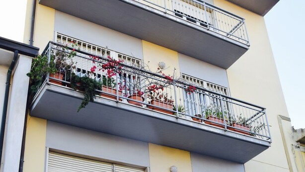Un edifici de diverses plantes amb balcons, alguns amb plantes i flors.