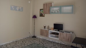 Un saló amb televisió, un armari i una làmpada de peu.