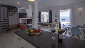 Una cocina moderna con una isla central, un comedor con vistas y una escalera en espiral.