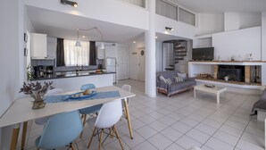 Un amplio salón con mesa de comedor, sillas, sofá y chimenea.