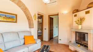 A living room with a sofa, a fireplace, and a painting on the wall. - Vinciluna 4, Emma Villas (Scanizza)