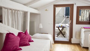 Camera da letto con due letti, pavimento in legno, balcone con tavolo e vista esterna.