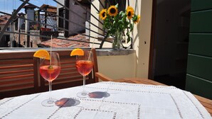 Un tavolo con due bicchieri di bevanda rossa, un vaso con girasoli e vista su edifici attraverso una struttura metallica.