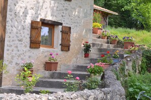 A stone building with wooden shutters, a window, and steps leading to a door. There are potted plants on the steps. - Pet friendly  3 bedroom house. (Saint Aulaye-Puymangou)