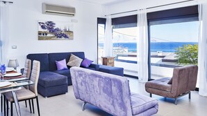 Uma sala de estar moderna com um sofá, poltronas e uma área de jantar.