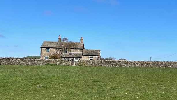 A stone house with a stone wall in front, set in a grassy field under a clear sky. - Far Reaching Rural Views- Pet Friendly  (Silsden)