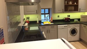 A modern kitchen with a stainless steel range hood, a built-in dishwasher, and a front-loading washing machine. - Far Reaching Rural Views- Pet Friendly  (Silsden)