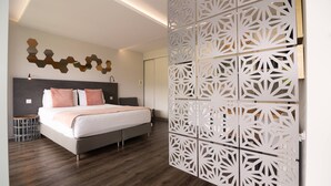 A modern bedroom with a large bed, a decorative wall panel, and a wooden floor. - Studio south lower-level w/ kitchenett and patio (Madeira)