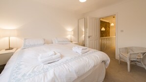 A hotel room with a large bed, two bedside lamps, a chair, and a door leading to a balcony. - London House, Chiswick, Luxurious, 3 Large Beds - 4 x Bath - GREAT PLACE TO STAY (London)