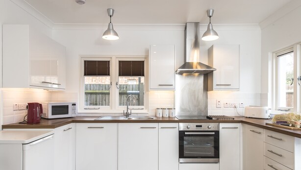 A modern kitchen with white cabinets, stainless steel appliances, and a window with blinds. - London House, Chiswick, Luxurious, 3 Large Beds - 4 x Bath - GREAT PLACE TO STAY (London)