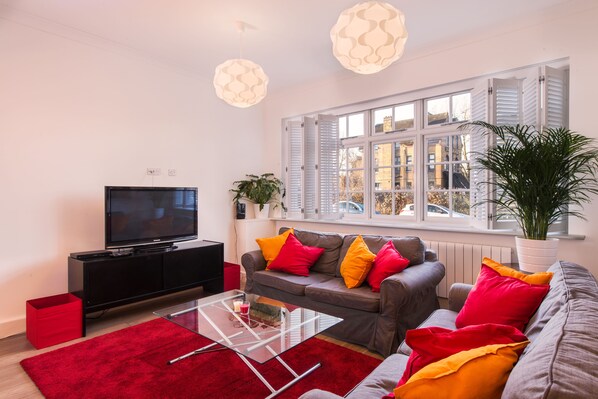 A modern living room with a television, sofa, and red rug.