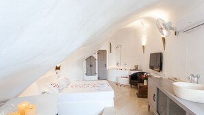 A modern, white-themed bedroom with a large bed, bedside tables, and a built-in TV. - Spacious Luxury Private Villa - Heated Pool - Ocean Views (santorini)