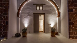 An arched entrance with a door, potted plants, and a small window above the door. - Spacious Luxury Private Villa - Heated Pool - Ocean Views (santorini)