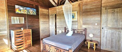 A wooden room with a bed, a dresser, a mirror, and a ceiling fan.