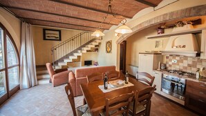 Amplia sala de estar con una mesa de comedor de madera, asientos cómodos, una escalera y una cocina con electrodomésticos modernos.