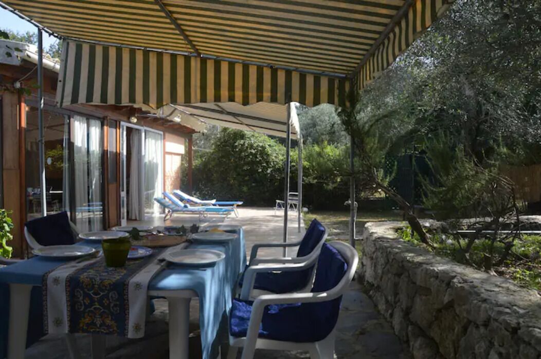 An outdoor patio with a covered seating area, a pool, and a stone wall.
