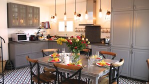 A dining area with a table set for four, surrounded by grey cabinets and a microwave. - Entire fully renovated town house sea-view rooftop terrace, AC for 6 (Antibes)
