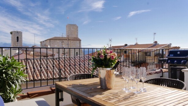 A terrace with a table set for dining, a grill, and a view of buildings and the sea. - Entire fully renovated town house sea-view rooftop terrace, AC for 6 (Antibes)