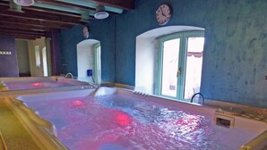 Un jacuzzi amplio en el interior, con suelo de baldosas y una ventana con vistas al exterior.