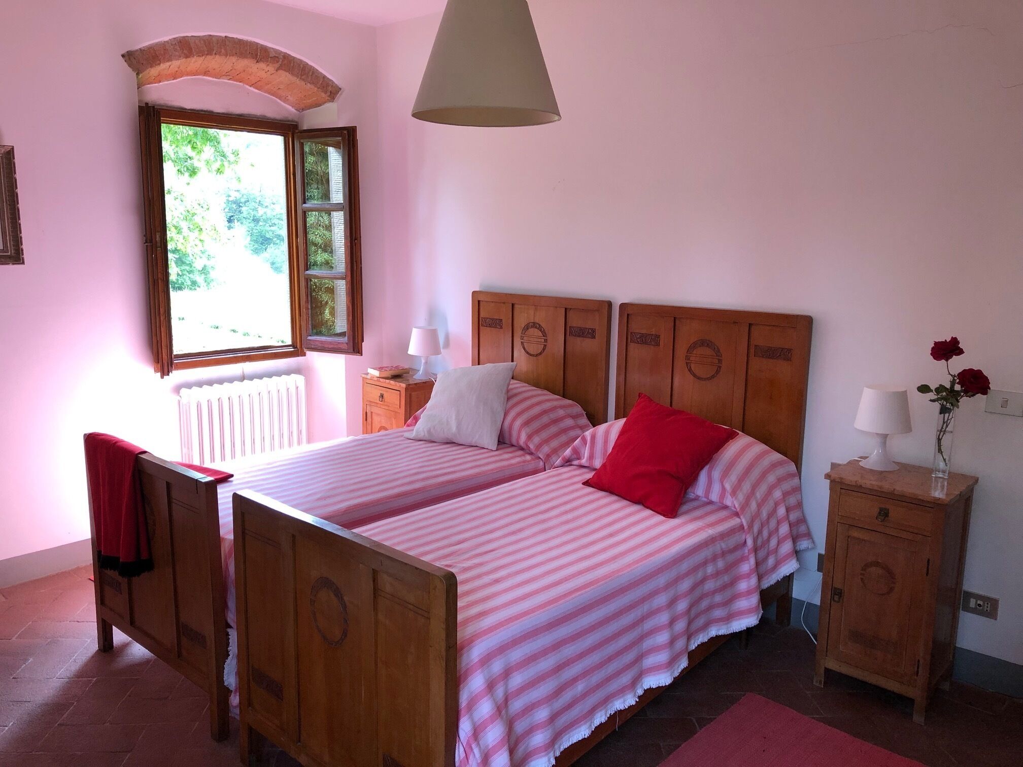 Ein Schlafzimmer mit zwei Betten, einem Holzkopfstück, einem Nachttisch, einem Stuhl, einem Fenster und einer Lampe.