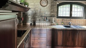 A kitchen with a stone wall, wooden cabinets, a window, and a hanging pot rack. - detached villa with a private swimming pool and a large terrain (Umbertide)