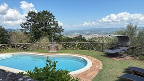 A swimming pool with a wooden deck, surrounded by a wooden fence and a view of a cityscape. - detached villa with a private swimming pool and a large terrain (Umbertide)