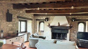A rustic interior with a stone wall, a fireplace, a sofa, and a television. - detached villa with a private swimming pool and a large terrain (Umbertide)