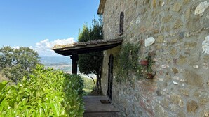 A stone building with a covered walkway, potted plants, and a view of the landscape. - detached villa with a private swimming pool and a large terrain (Umbertide)