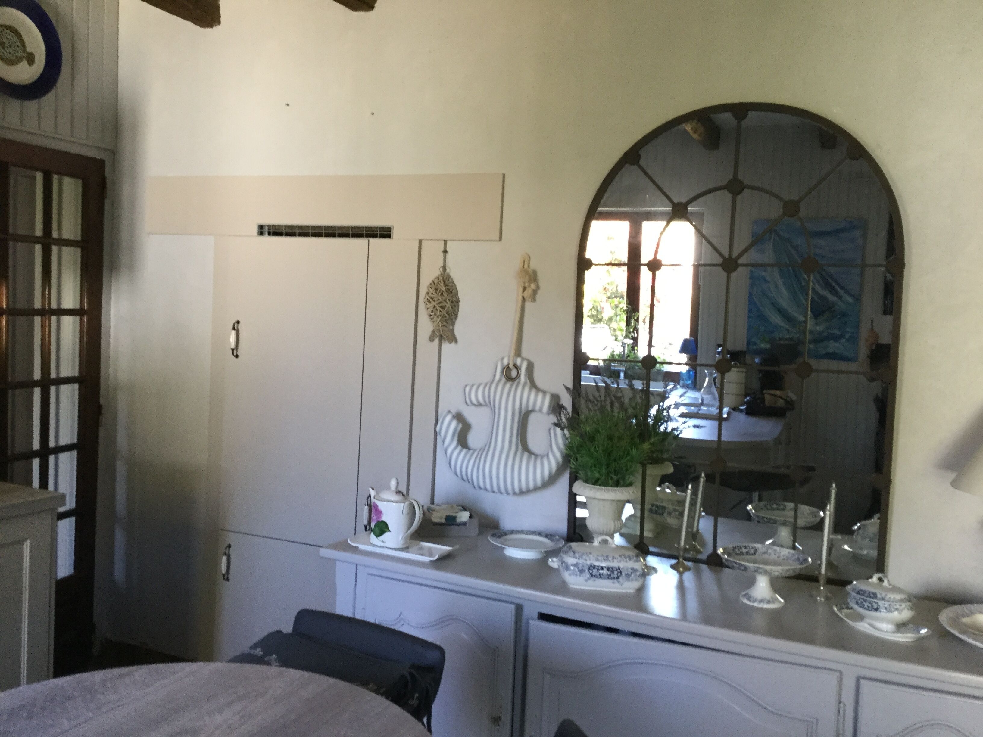 A room with a white dresser, a mirror, a hanging fish decoration, and a potted plant.