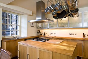 Een moderne keuken met houten kastjes, een roestvrijstalen afzuigkap en een raam met uitzicht.