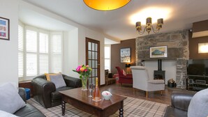 A cozy living room with a fireplace, a sofa, a coffee table, and a television. - Awelon sleeps 10, Hot Tub, Log Burner, private courtyard, Porthmadog, Snowdonia (porthmadog)