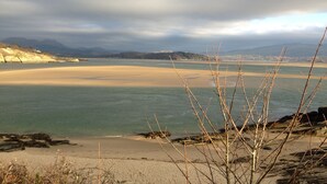 A coastal landscape with a sandy beach, calm water, and distant mountains under a cloudy sky. - Awelon sleeps 10, Hot Tub, Log Burner, private courtyard, Porthmadog, Snowdonia (porthmadog)