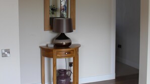 A hallway with a wooden console table, a lamp, and a mirror.